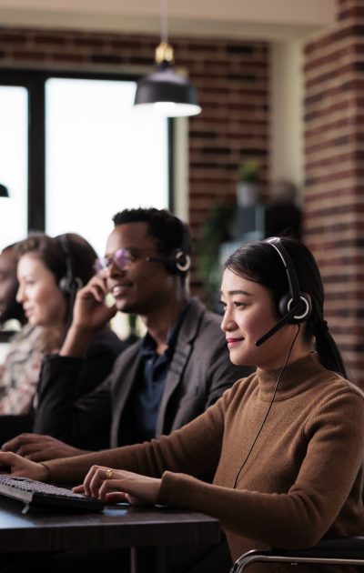 Paralyzed asian receptionist working at call center helpdesk in disability friendly office. Female operator wheelchair user with impairment giving assistance on customer service helpline.